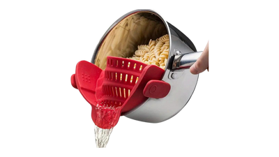 Red silicone pot strainer attached to a pot of pasta.